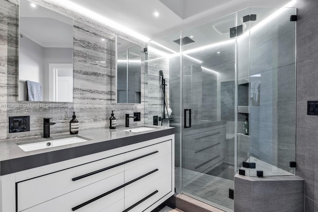 full bath with double vanity, tile walls, a shower stall, and a sink