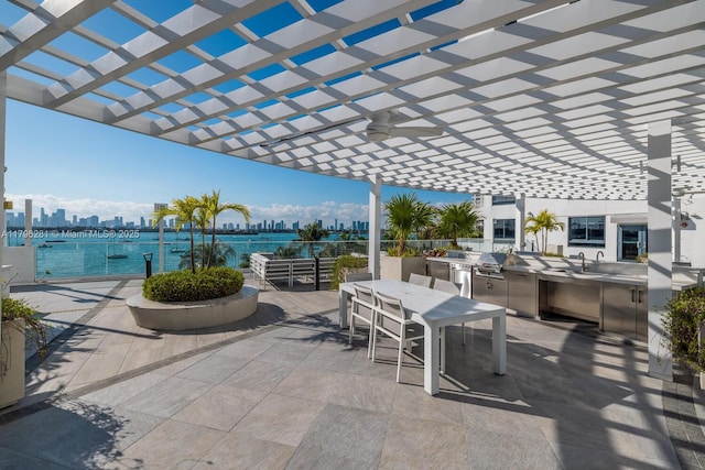 view of patio / terrace featuring a ceiling fan, a pergola, outdoor dining space, an outdoor kitchen, and a city view