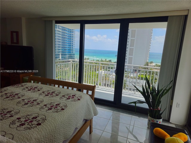 bedroom with a water view, a textured ceiling, light tile patterned floors, and access to outside