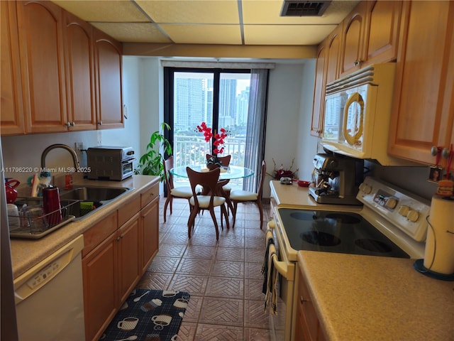 kitchen with visible vents, a sink, white appliances, and light countertops