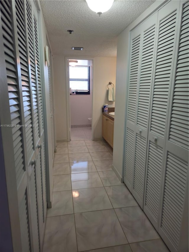 hallway with a textured ceiling and baseboards