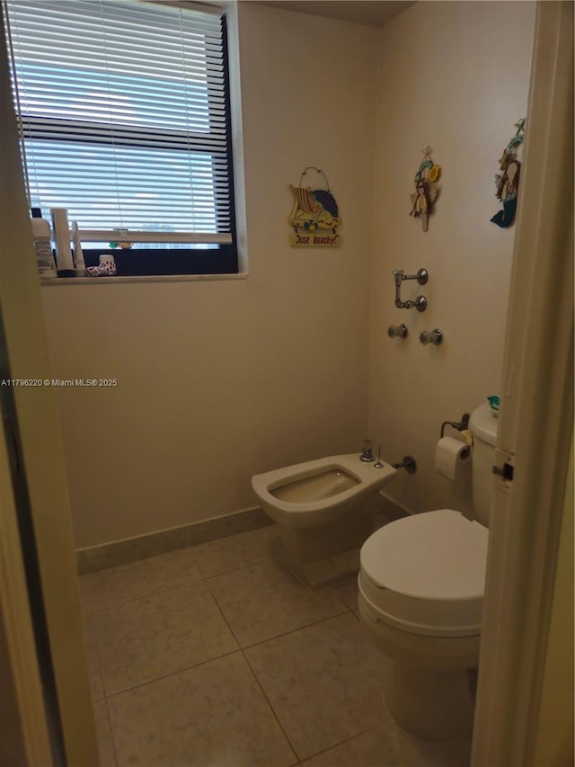 bathroom featuring toilet, baseboards, a bidet, and tile patterned flooring