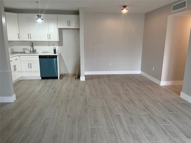 kitchen with visible vents, baseboards, light wood-type flooring, light countertops, and dishwasher