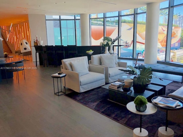 living area with floor to ceiling windows, wood finished floors, and stairway