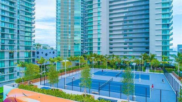 view of tennis court featuring a view of city and fence