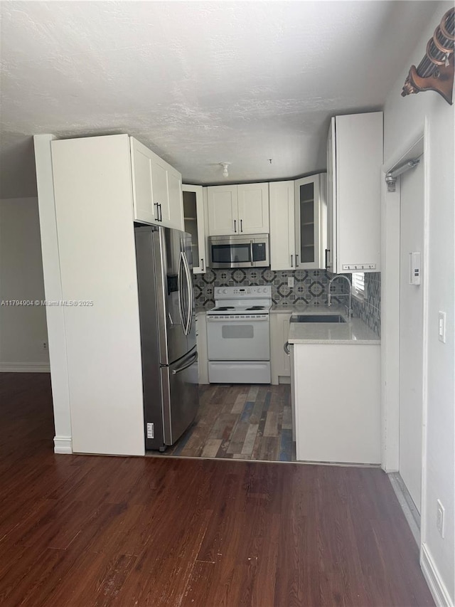 3800 NE 21st Ave Unit 12, Lighthouse Point, FL 33064 - kitchen featuring glass insert cabinets, dark wood-type flooring, light countertops, a sink, and appliances with stainless steel finishes