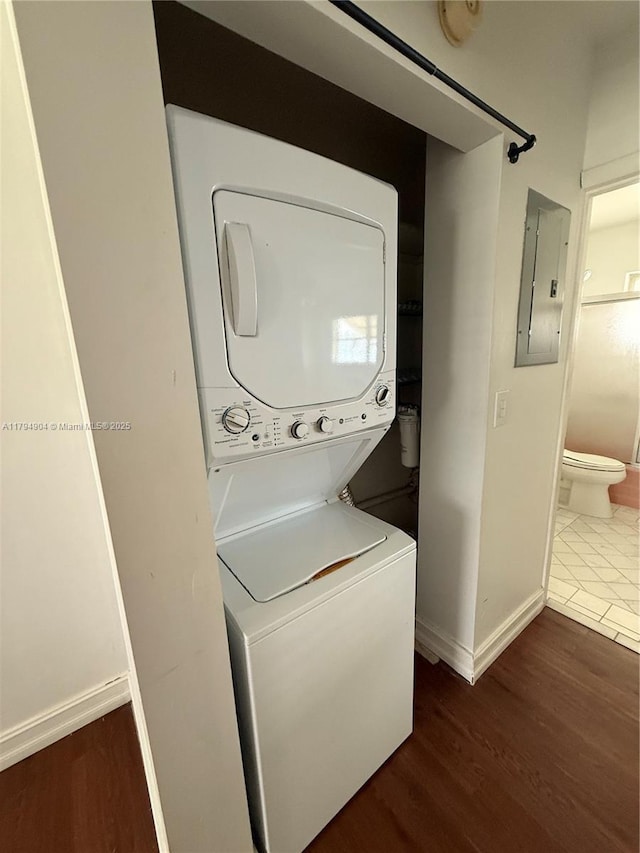 3800 NE 21st Ave Unit 12, Lighthouse Point, FL 33064 - laundry room with stacked washer and dryer, laundry area, baseboards, wood finished floors, and electric panel