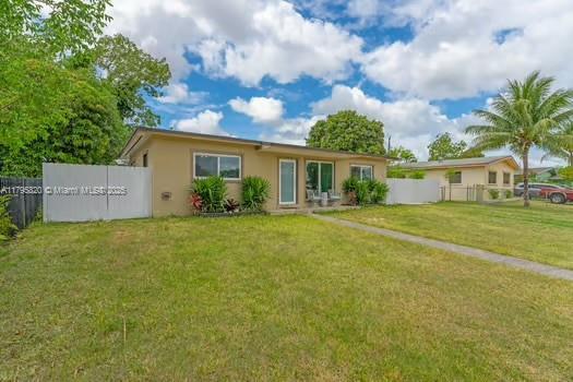 view of front of home featuring stucco siding, fence, and a front lawn