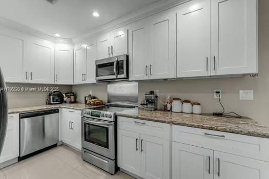 kitchen featuring light stone countertops, recessed lighting, white cabinets, light tile patterned floors, and stainless steel appliances
