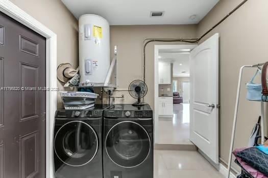 laundry room with washing machine and clothes dryer, laundry area, visible vents, and water heater