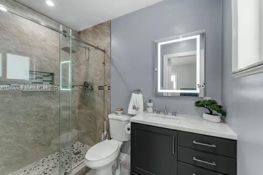 full bathroom with toilet, a shower stall, and vanity