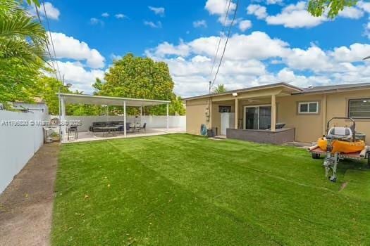rear view of property featuring a yard, a fenced backyard, a patio area, and stucco siding