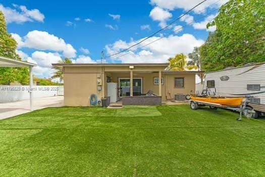 rear view of property with a lawn, stucco siding, and central air condition unit