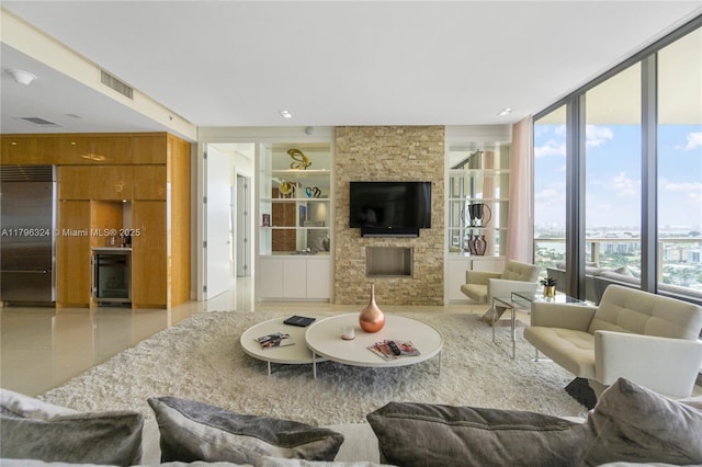 living room featuring tile patterned flooring, a stone fireplace, wine cooler, visible vents, and expansive windows