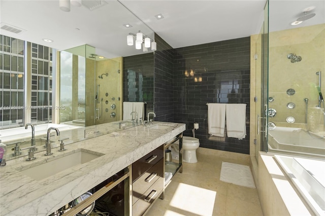 bathroom featuring a sink, a stall shower, toilet, and tile walls