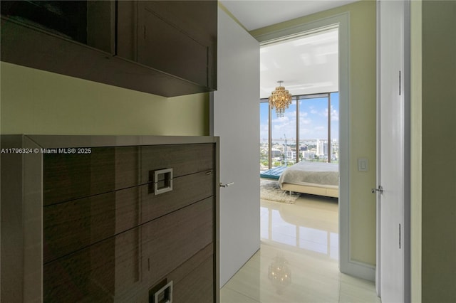 hall featuring expansive windows, light tile patterned floors, and an inviting chandelier