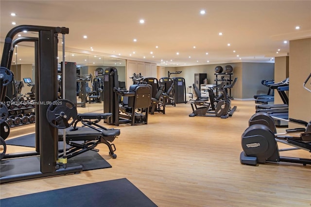 workout area with recessed lighting and light wood finished floors