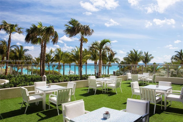 view of property's community with outdoor dining area and a lawn