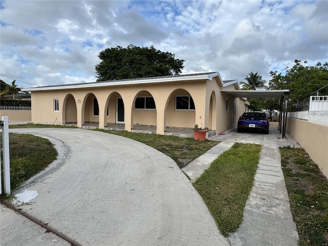 mediterranean / spanish-style home with fence, a carport, stucco siding, and driveway