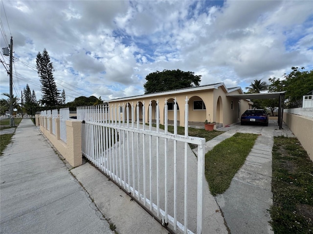 view of front of house with a fenced front yard, stucco siding, driveway, and a carport