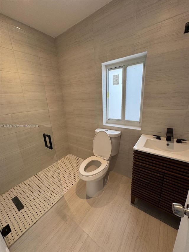 full bath with vanity, tile walls, toilet, and a shower stall