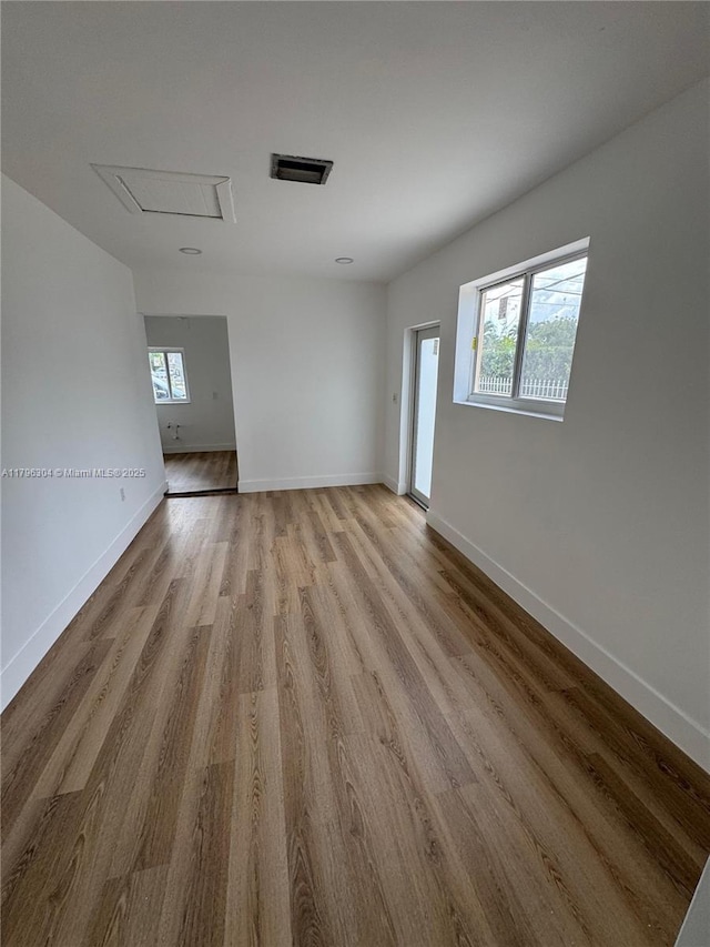 empty room featuring baseboards, light wood finished floors, and visible vents
