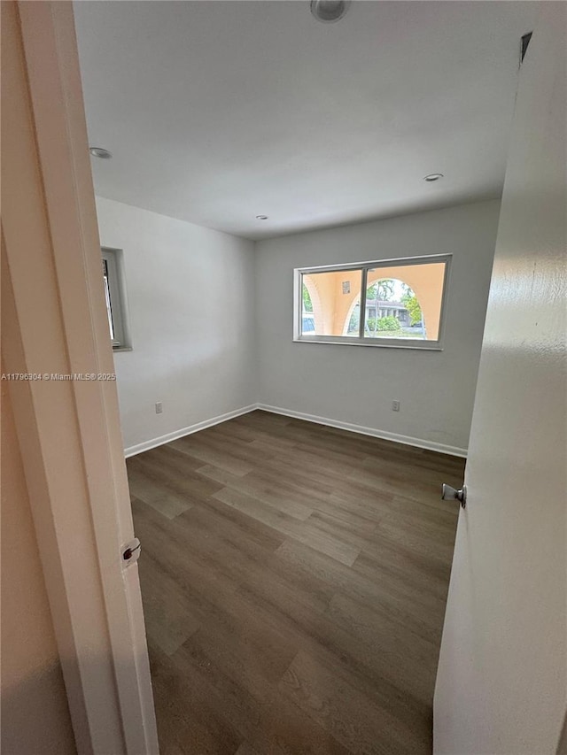 unfurnished room with baseboards and wood finished floors