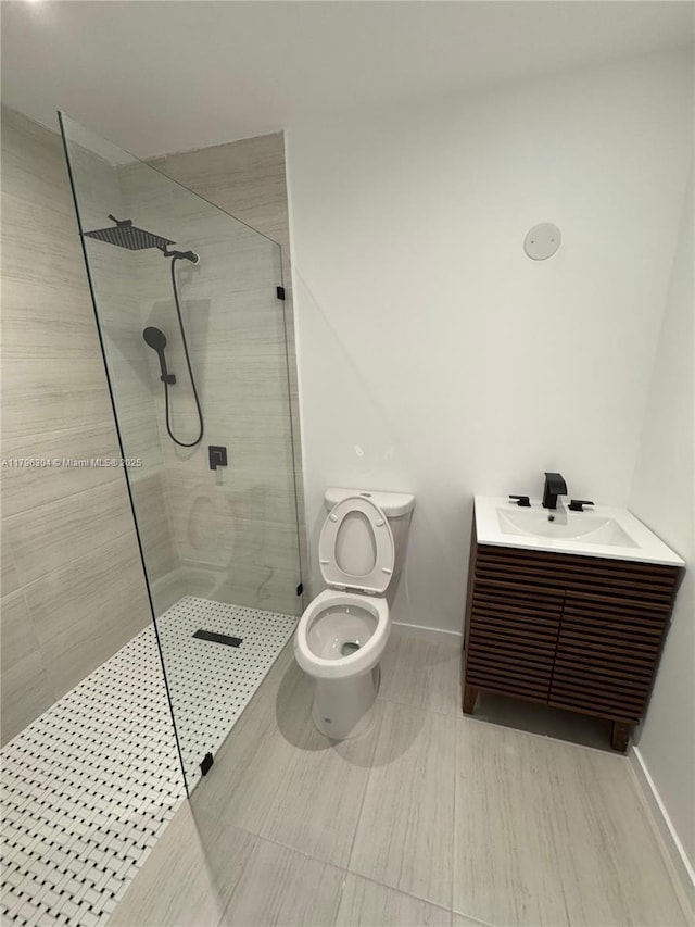 full bathroom featuring toilet, baseboards, walk in shower, and vanity