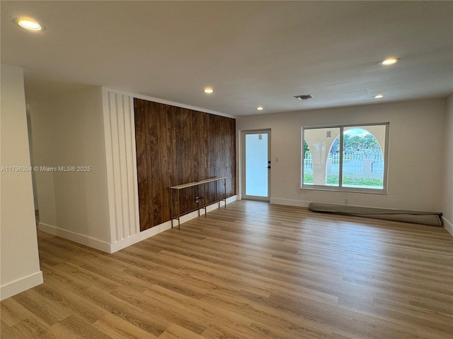 empty room with light wood-style floors, recessed lighting, baseboards, and visible vents