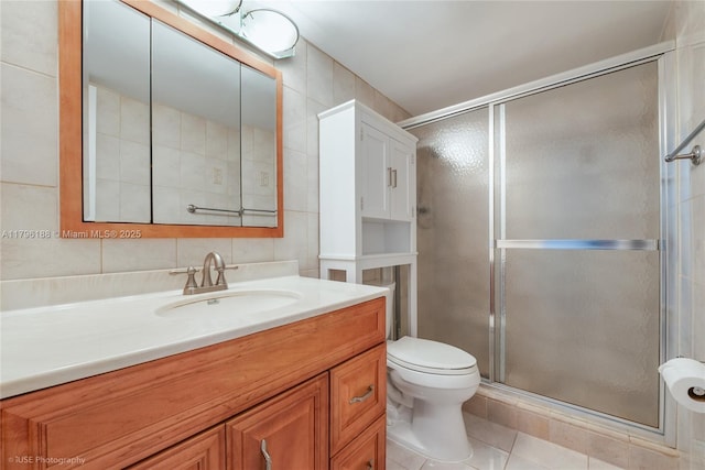 bathroom featuring toilet, tile walls, vanity, tile patterned floors, and a stall shower