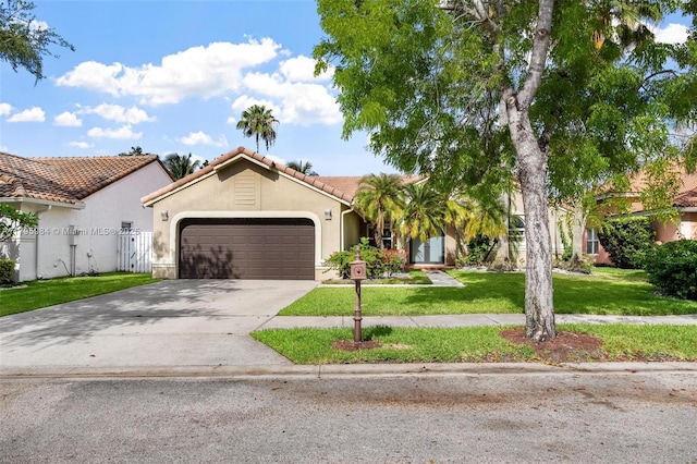 mediterranean / spanish-style house featuring an attached garage, concrete driveway, stucco siding, a front yard, and a tiled roof