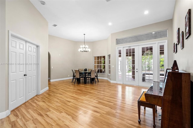 dining room with an inviting chandelier, baseboards, french doors, and light wood-style floors