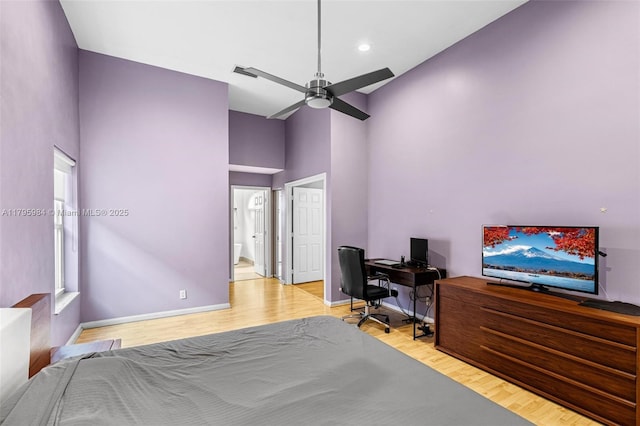 bedroom with baseboards, recessed lighting, a high ceiling, and wood finished floors