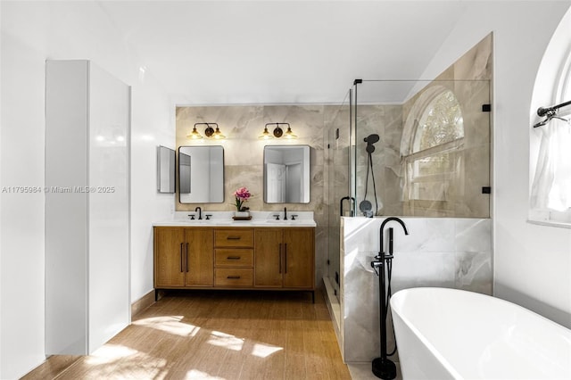 full bathroom with tile walls, a sink, a shower stall, a soaking tub, and double vanity