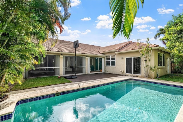 back of house with stucco siding, a sunroom, a tiled roof, and an outdoor pool
