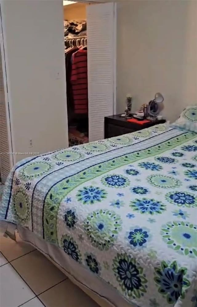 tiled bedroom featuring a walk in closet and a closet
