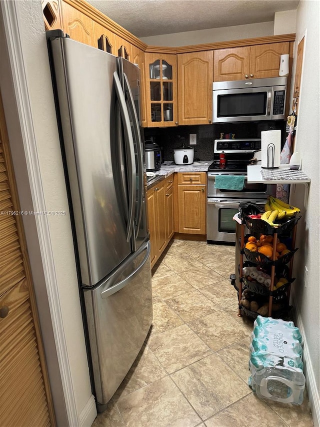 kitchen featuring light countertops, appliances with stainless steel finishes, and glass insert cabinets