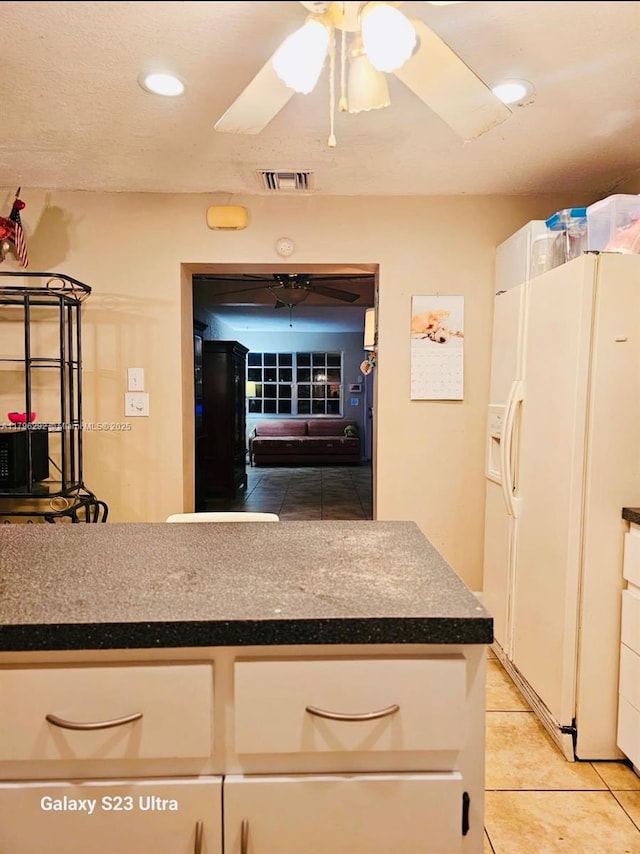 5706 Simms St, Hollywood, FL 33021 - kitchen featuring white fridge with ice dispenser, light tile patterned flooring, dark countertops, recessed lighting, and white cabinetry