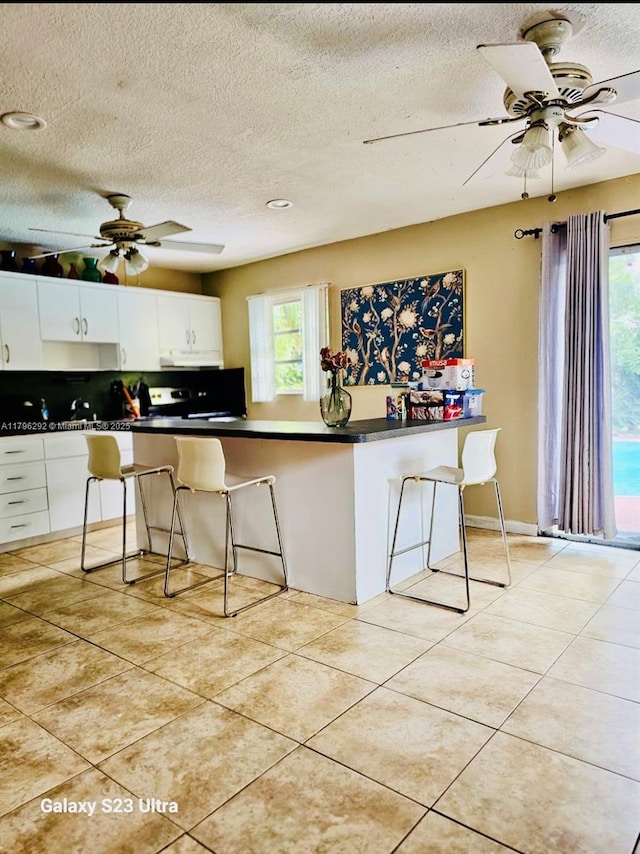 5706 Simms St, Hollywood, FL 33021 - kitchen featuring ceiling fan, dark countertops, light tile patterned floors, white cabinets, and a textured ceiling