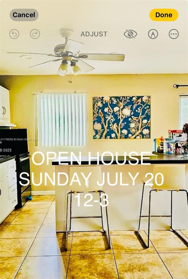 5706 Simms St, Hollywood, FL 33021 - kitchen with light tile patterned floors, ceiling fan, white cabinets, under cabinet range hood, and range with electric cooktop