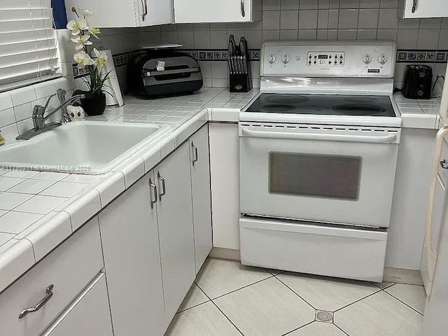 6620 W 2nd Ct Unit 407, Hialeah, FL 33012 - kitchen with electric stove, tile counters, white cabinetry, and backsplash