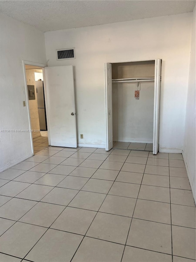4550 NW 9th St Unit 114E, Miami, FL 33126 - unfurnished bedroom featuring freestanding refrigerator, a closet, and light tile patterned flooring