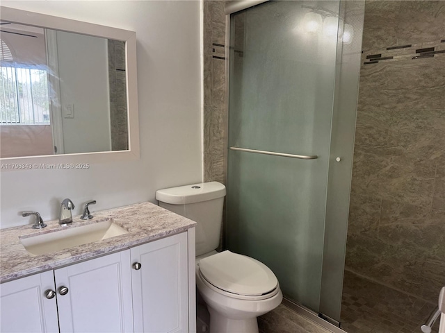 bathroom featuring vanity, toilet, and a stall shower