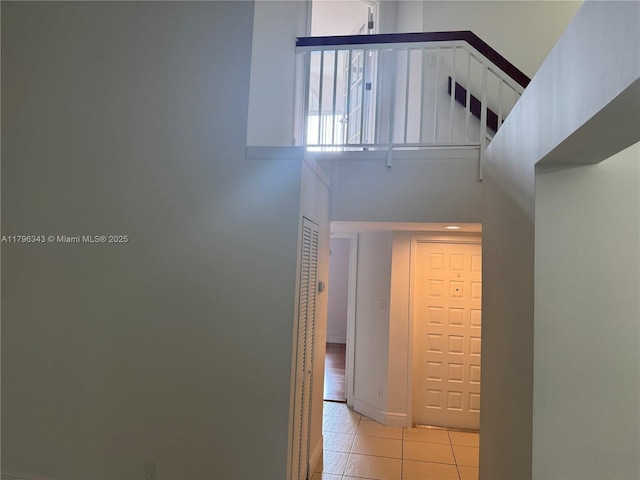 hallway with a high ceiling and light tile patterned floors