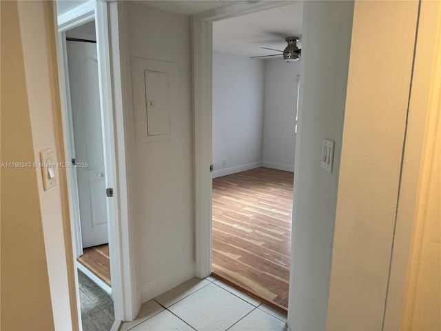 corridor featuring light tile patterned floors and baseboards
