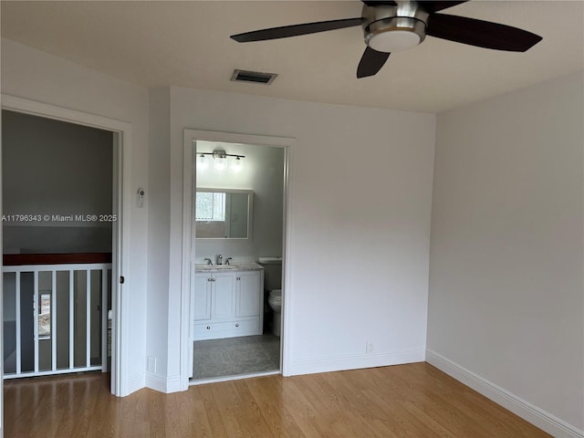 unfurnished bedroom with baseboards, visible vents, a sink, and wood finished floors