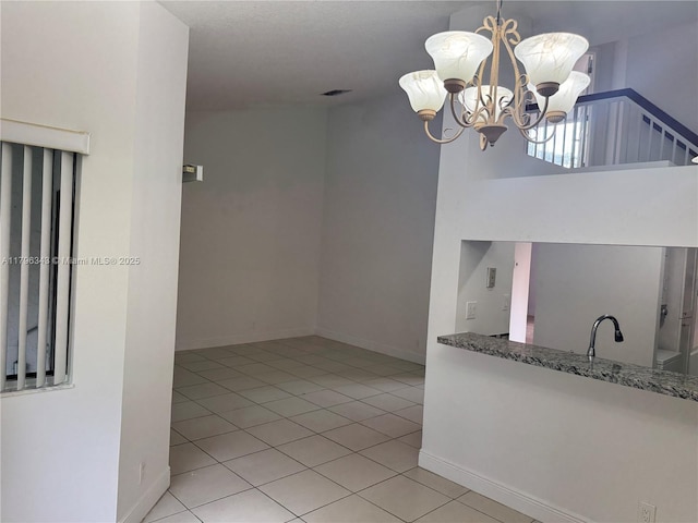 kitchen with baseboards, a notable chandelier, stone countertops, and light tile patterned floors