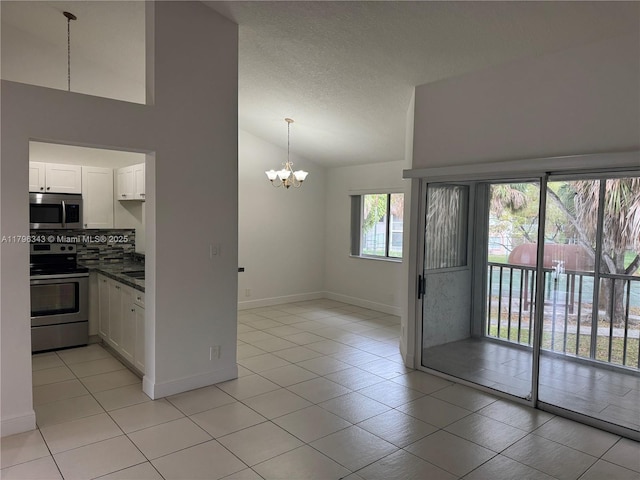 kitchen featuring dark countertops, appliances with stainless steel finishes, a chandelier, white cabinetry, and decorative backsplash