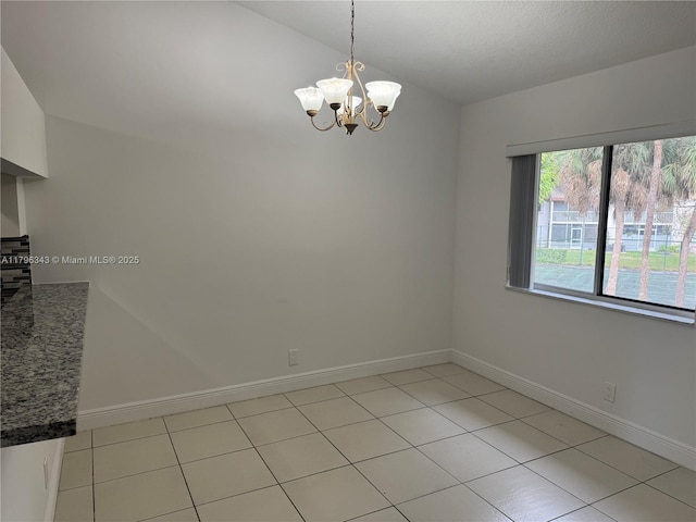 unfurnished room with an inviting chandelier, baseboards, light tile patterned floors, and lofted ceiling