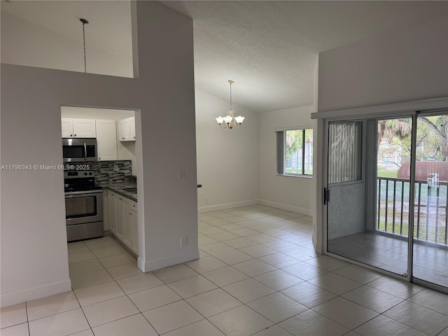 kitchen with decorative backsplash, appliances with stainless steel finishes, vaulted ceiling, white cabinets, and a notable chandelier
